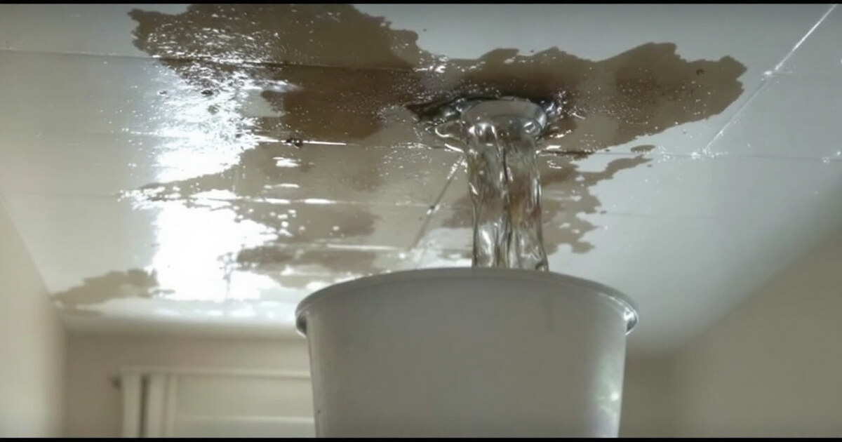 Water leaking from an apartment ceiling into a bucket on the floor